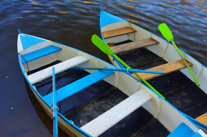 Two blue row boats anchored in a river shore