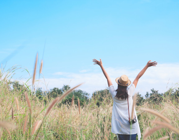 woman traveler with camera push hands and breathing at field of grasses and forest, wanderlust travel concept, space for text, atmosperic epic moment