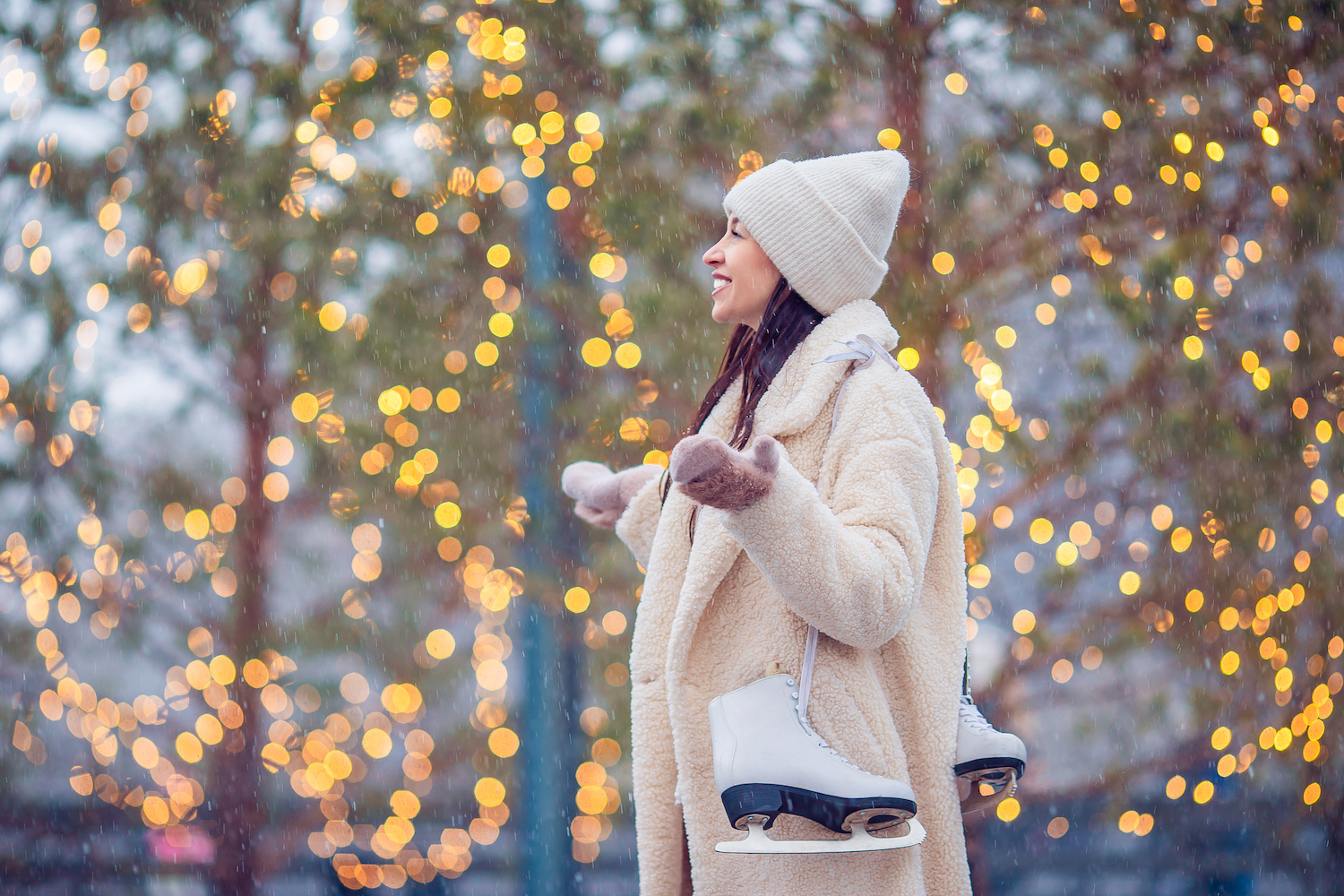 Happy young woman ready to skate on ice rink outdoors