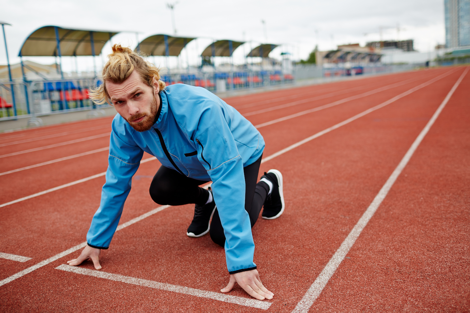 Young sportsman looking at camera while standing by start line and getting ready to run